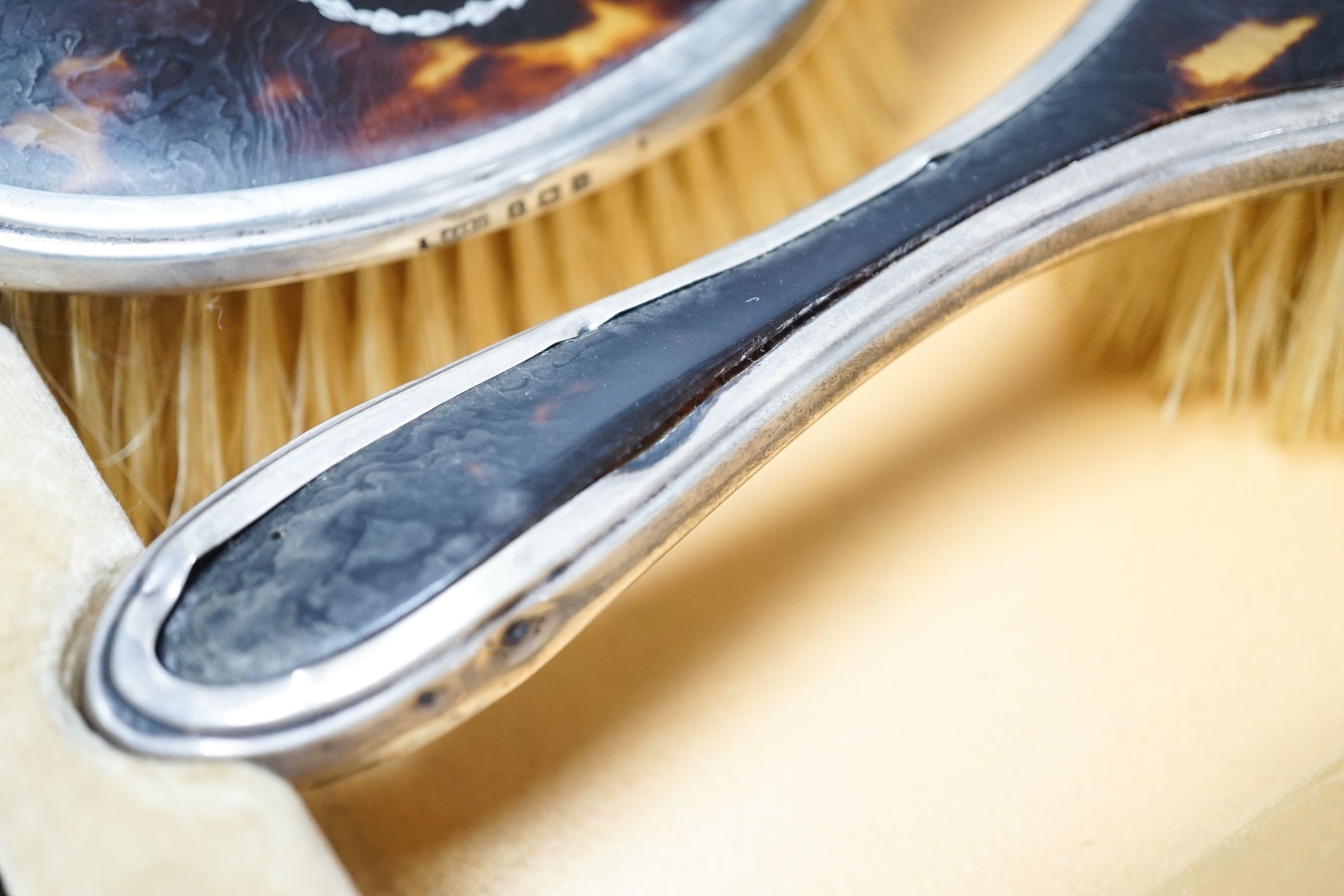 A 1920's cased tortoiseshell and silver mounted mirror and brush set.